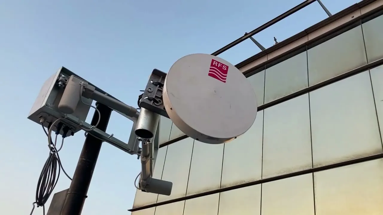 Posicionador moviendo una antena RFS frente a una fachada de vidrio